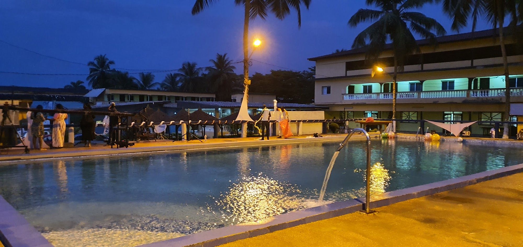 La piscine éclairée à la tombée de la nuit, devant l'hôtel