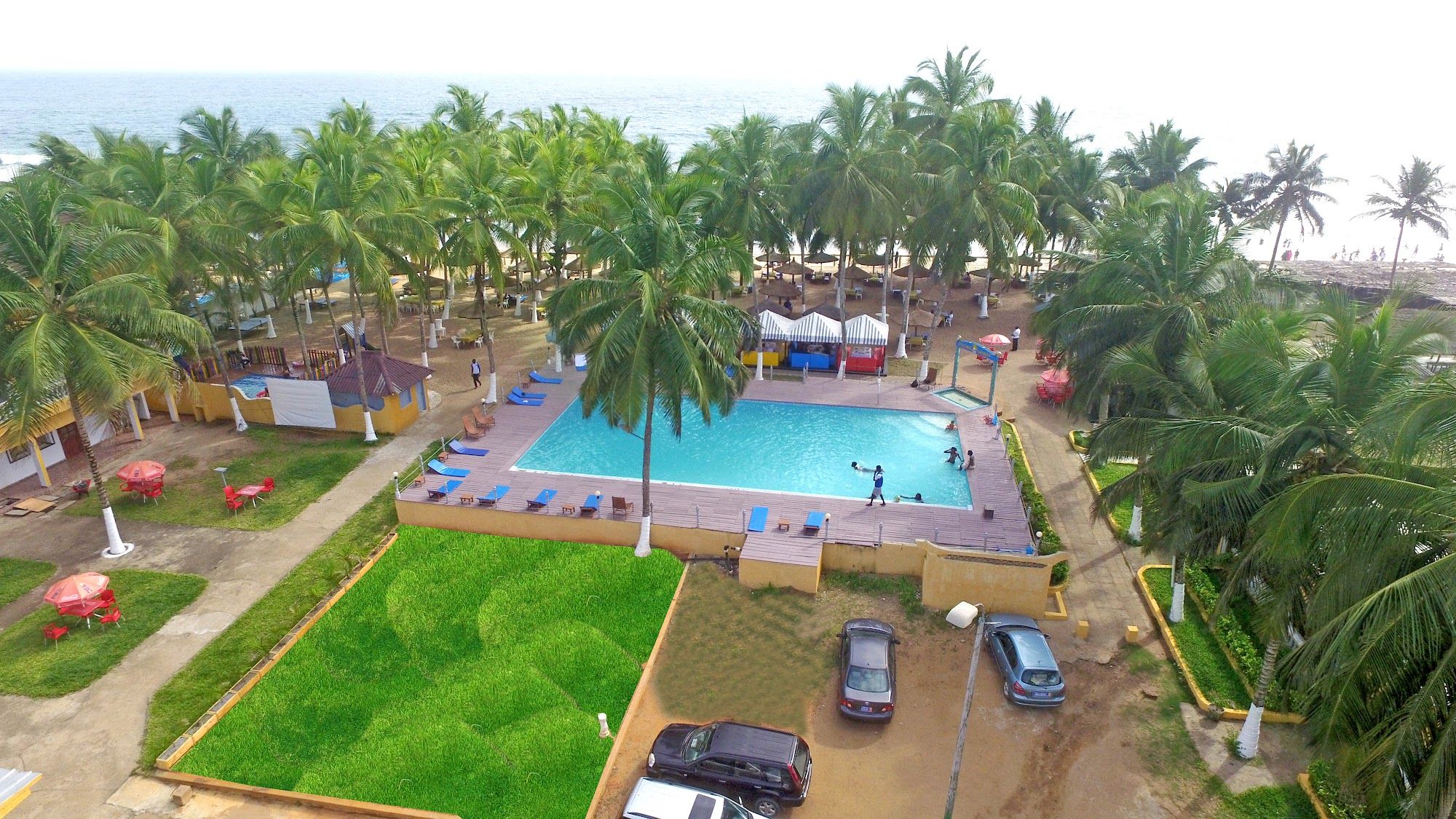 Vue du ciel : la piscine, les jardins et les cocotiers jusqu'à la mer